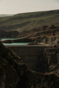 A striking view of a large dam amid rolling hills, capturing the interplay of light and shadow.